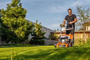 Man mowing lawn in the backyard of his house