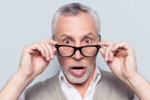 Surprised old man taking off and on his glasses