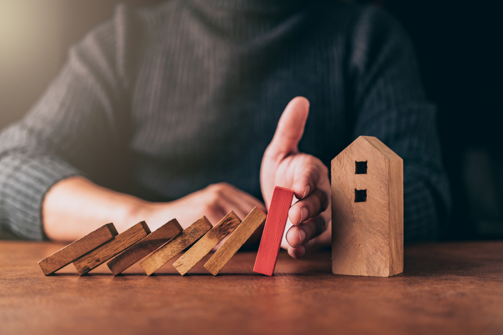 Man hand protect house wooden model
